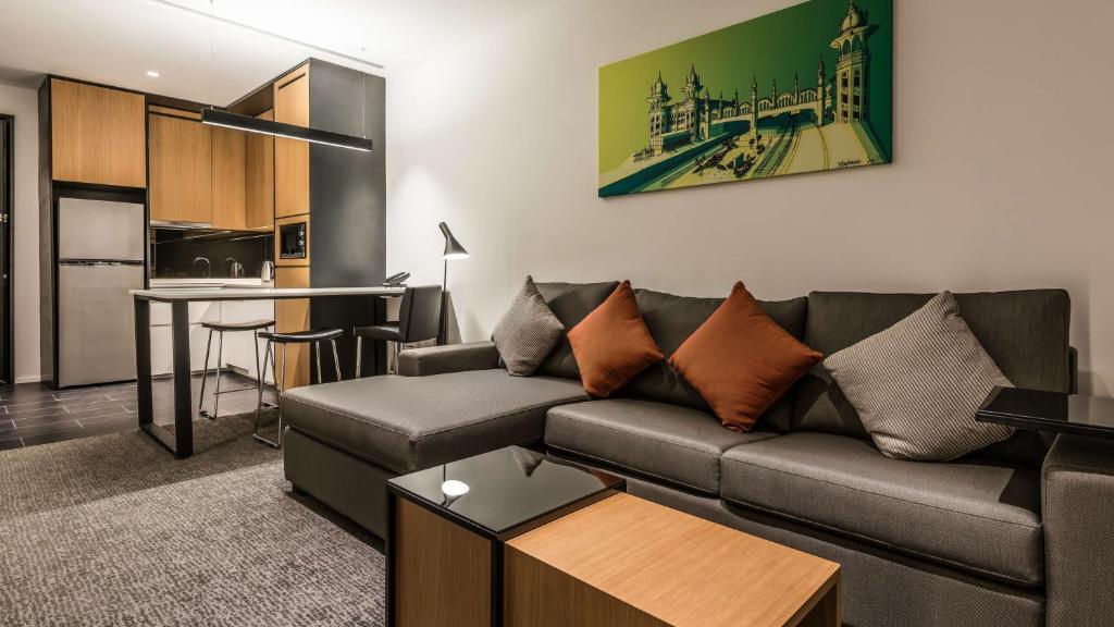A furnished suite living area with a sectional sofa, coffee tables and kitchenette.