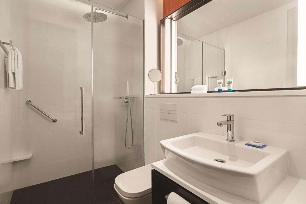 A bright bathroom with a walk-in glass shower and pedestal-style sink.