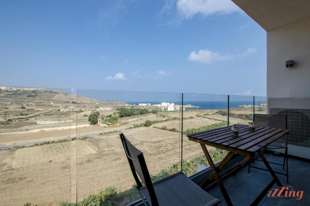 balcone con tavolo, sedie e vista sull'oceano di 2 Bed Apartment w Distant Sea and Country Views a Marsalforn