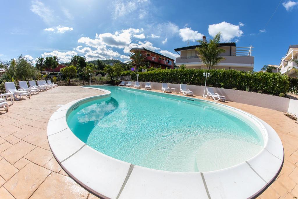 a swimming pool with lounge chairs and a building at Residenza Borgo Italico in Santa Domenica