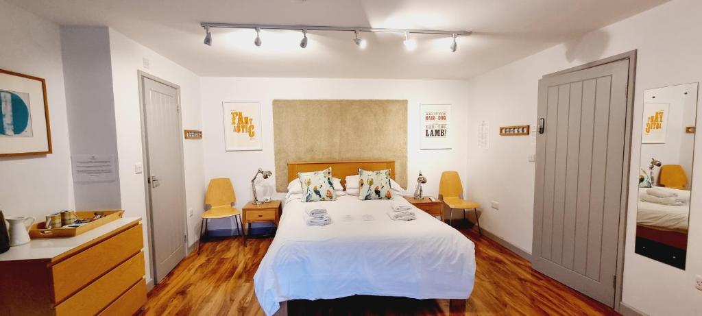 a bedroom with a large bed with white sheets and yellow chairs at B - Simply Rooms in Stow on the Wold