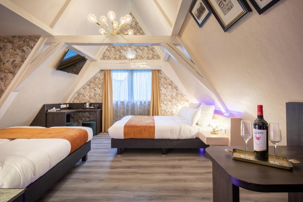 a bedroom with two beds and a desk with a bottle of wine at Hotel Oscar in Amsterdam