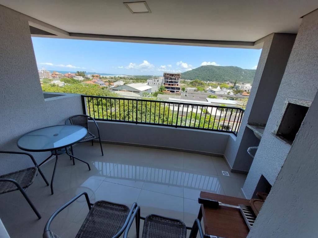 balcón con mesa y sillas y ventana grande en Apartamento perfeito para descansar, en Imbituba