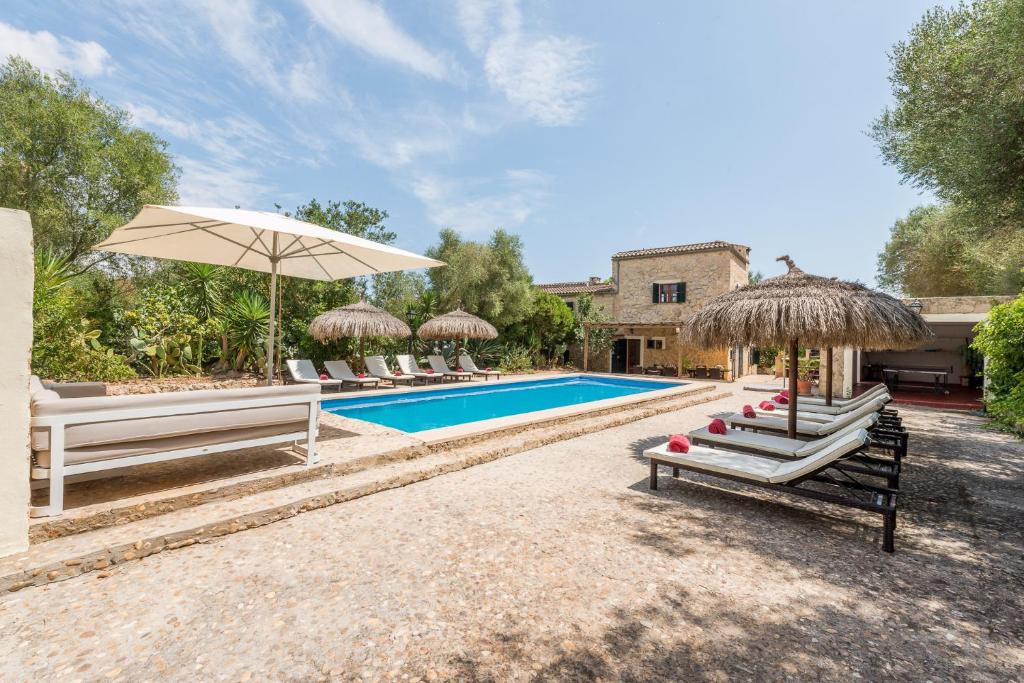 a pool with chairs and umbrellas next to a house at Finca Es Rafalot de Dalt by Mallorca House Rent in Manacor