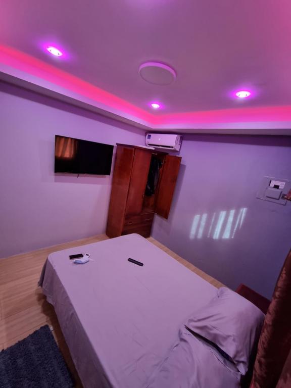 ein Schlafzimmer mit einem Bett mit rosa Lichtern in der Unterkunft Trésor Caché TT in Claxton Bay