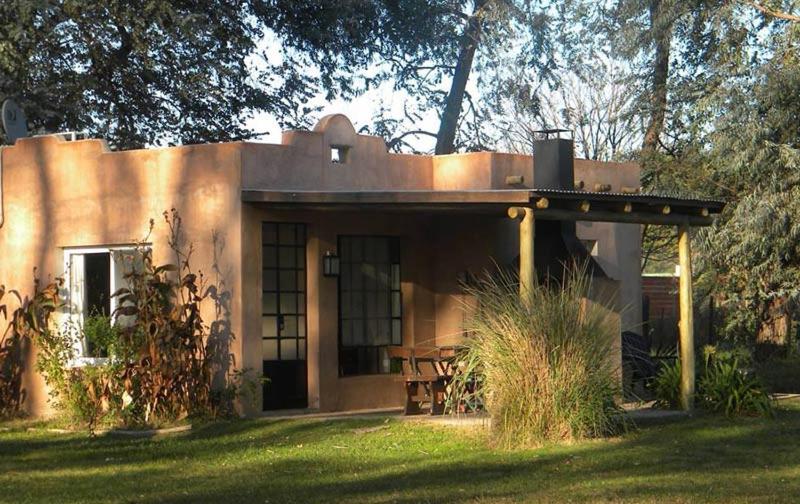 une petite maison avec une terrasse couverte sur une pelouse dans l'établissement La Pausa Lodge de Campo, à Duggan