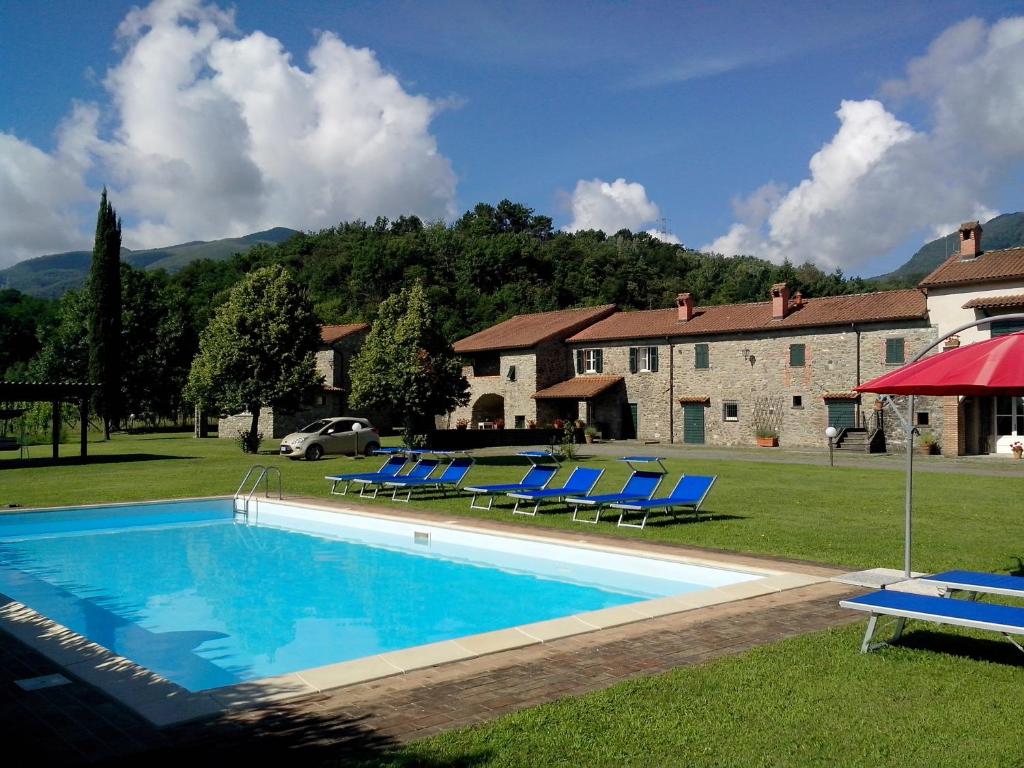 une piscine avec des chaises bleues et un bâtiment dans l'établissement Coriana Apartments & Villas, à Mulazzo