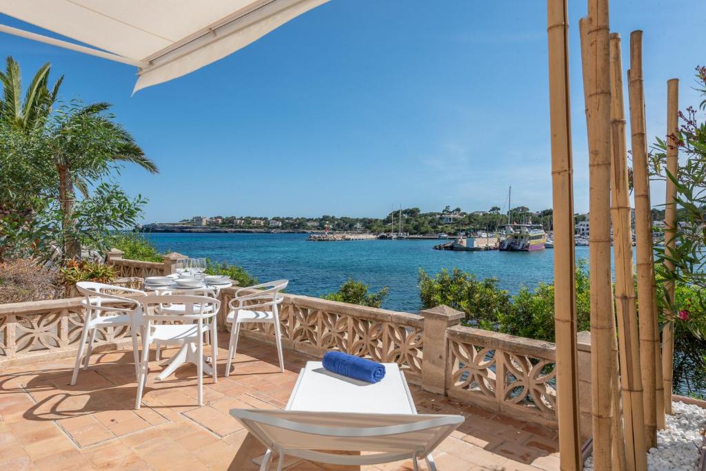 d'une terrasse avec une table, des chaises et l'eau. dans l'établissement Apartment Sa Caseta 3 by Mallorca House Rent, à Portopetro