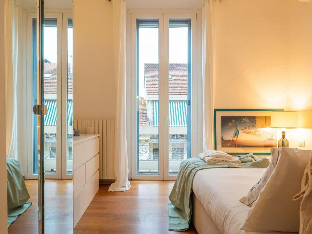 Schlafzimmer mit großen Fenstern und einem Bett mit weißer Bettwäsche in der Unterkunft The Best Rent - Apartment near Navigli in Mailand