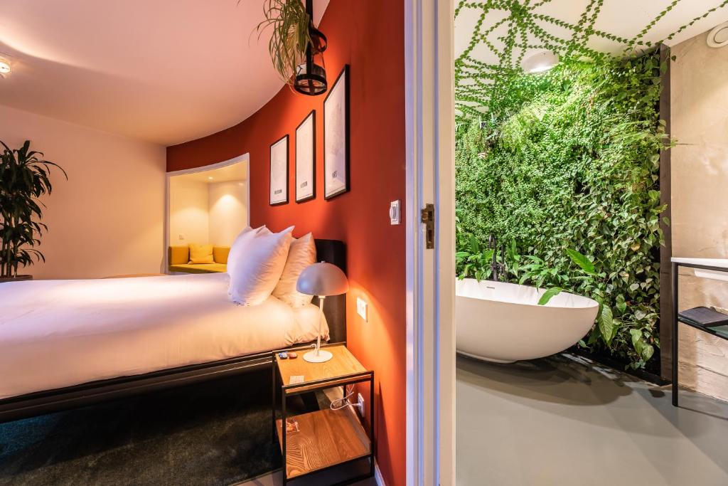 - une chambre avec un grand lit et une salle de bains pourvue d'une baignoire dans l'établissement Gooiland Hotel, à Hilversum