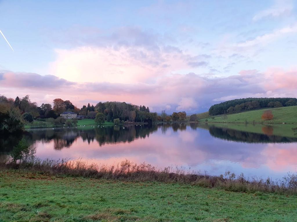 a view of a lake with the sun setting at The Coniston Hotel Country Estate & Spa - Skipton in Gargrave