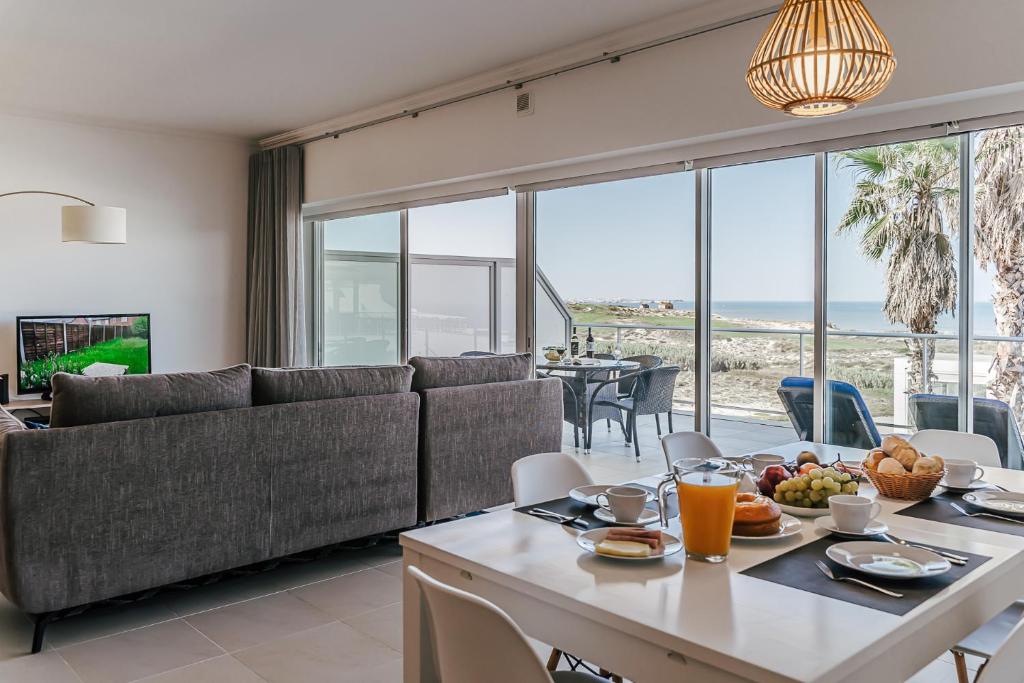 een woonkamer met een bank en een tafel met eten bij Beachfront Atlantic View A09 in Óbidos