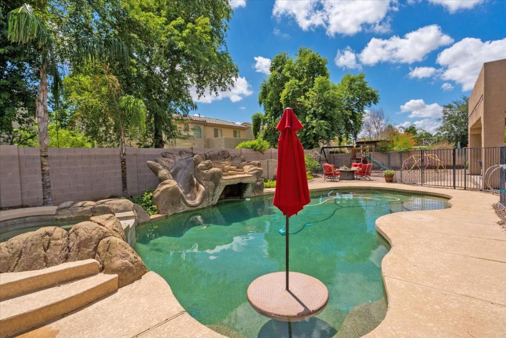 a pool with a red umbrella in a yard at Grand Ironhorse in Queen Creek