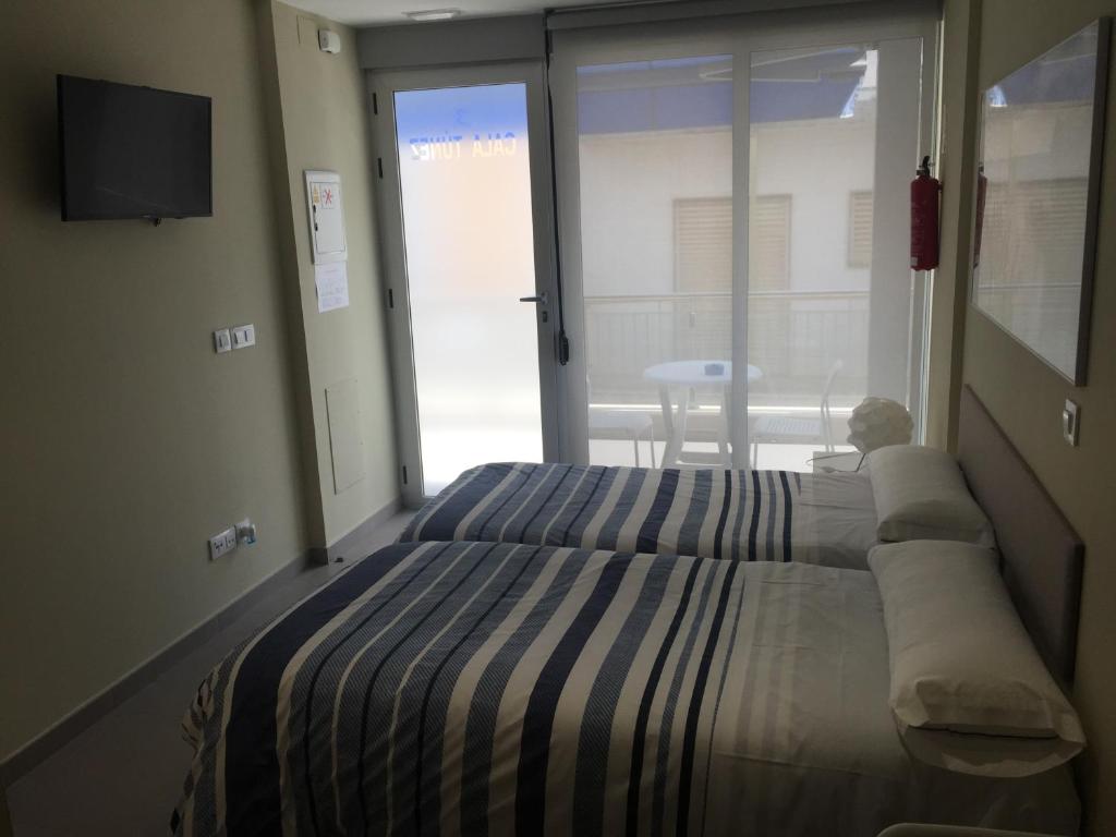 パロス岬にあるApartamentos Turisticos Maria Guerreroのベッドルーム1室(ベッド1台付)、スライド式ガラスドアが備わります。