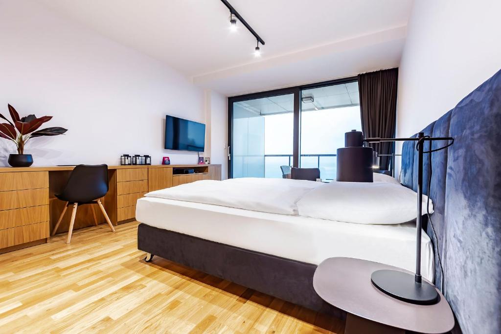a bedroom with a bed and a desk and a tv at VacationClub – Seaside Apartament 505 in Kołobrzeg