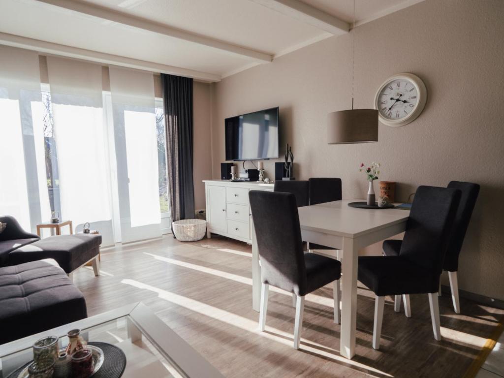 uma sala de estar com mesa e cadeiras e um relógio em Beachcomber House A em Friedrichskoog