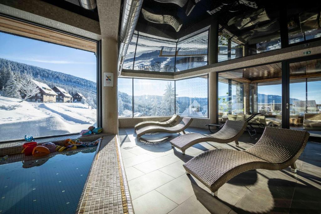 um quarto com uma piscina com cadeiras e vista para a montanha em Resort Sv. František - Hotel Erlebachova Bouda em Spindleruv Mlyn