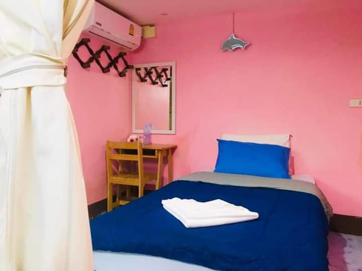 a bedroom with a blue bed with a pink wall at Sea Shell Hut in Phi Phi Don