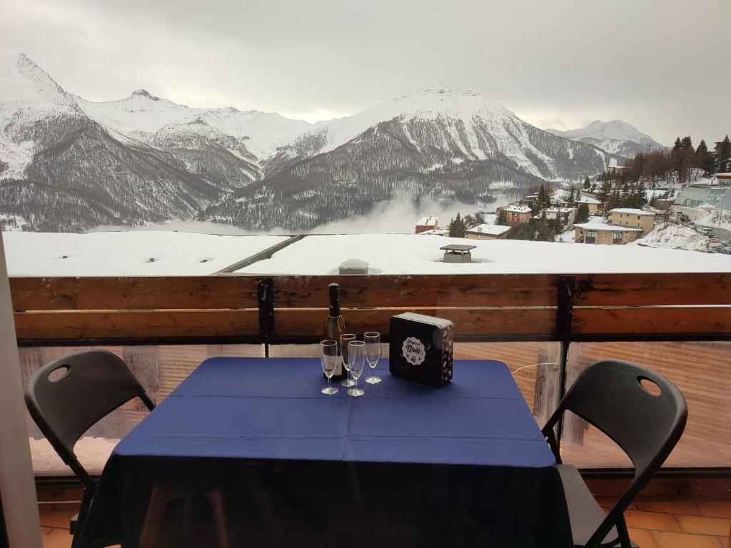 une table sur un balcon avec vue sur une montagne enneigée dans l'établissement LE COSY aux pieds des pistes appartement avec balcon PLEIN CENTRE, à Orcières