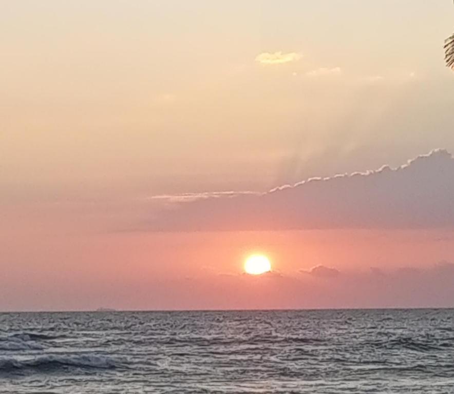 una puesta de sol sobre el océano con el sol en el cielo en Rainbow Surf Beach, en Koggala