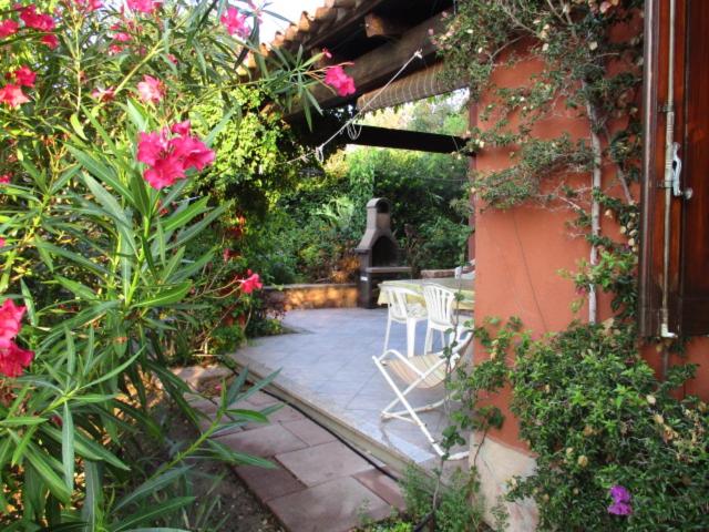 een patio met een tafel, stoelen en bloemen bij Maison de vacances dans un village de vacances à100 m. de la plage in Badesi