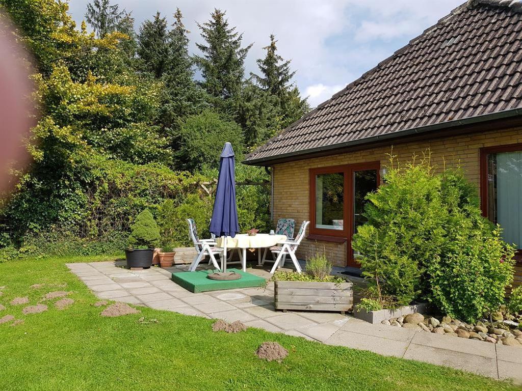 een patio met een tafel en een blauwe parasol bij Anneli's Ferienwohnung in Harrislee