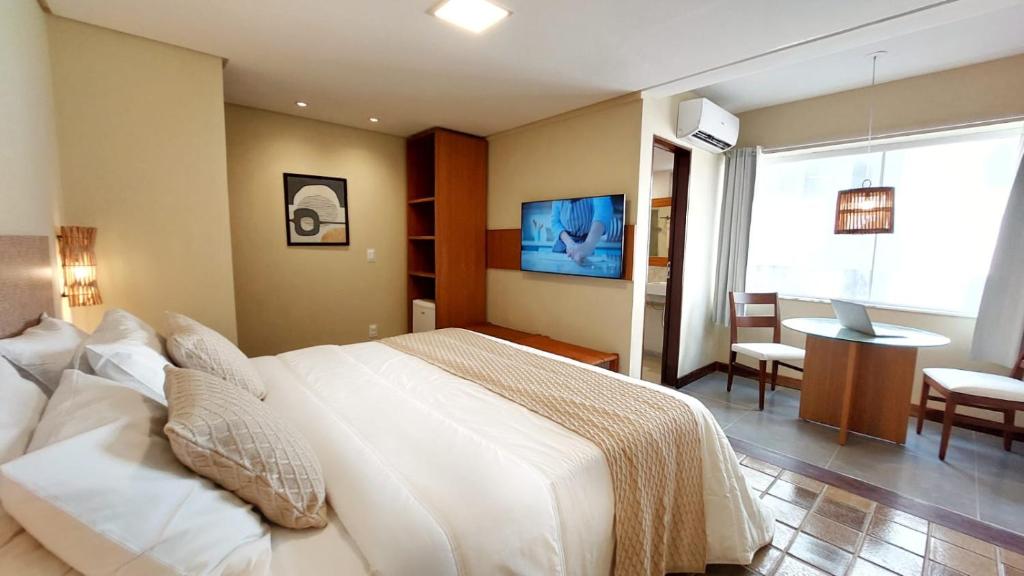 a bedroom with a large white bed and a table at Kastel Jampa Hotel in João Pessoa