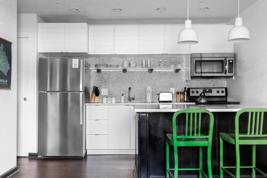 a kitchen with green chairs and a stainless steel refrigerator at SoBro Guest House by Black Swan in Nashville