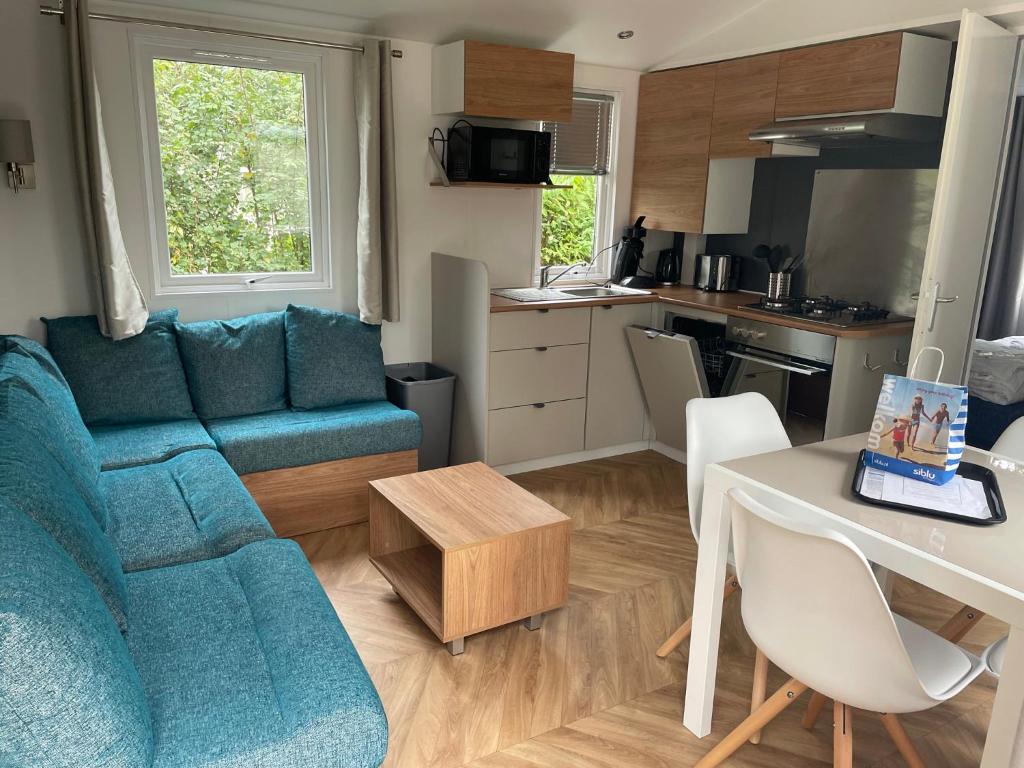 a living room with a blue couch and a kitchen at Renesse Chalet in family friendly area in Renesse