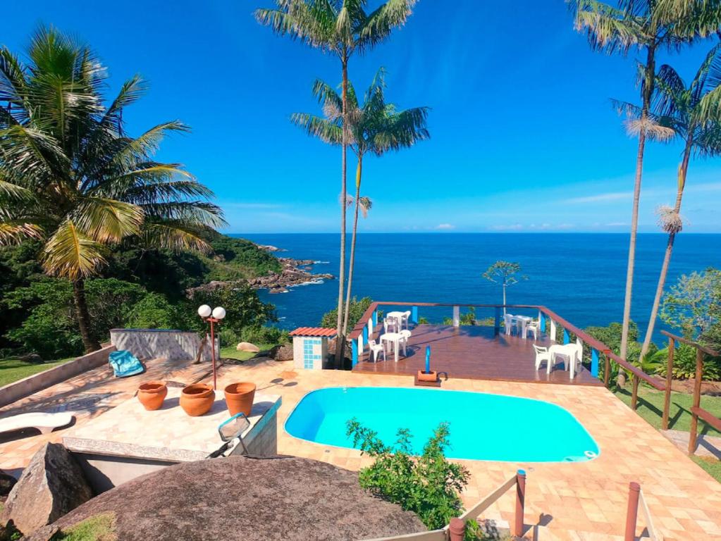 a swimming pool with the ocean in the background at Pousada Refúgio Caiçara in Ilhabela