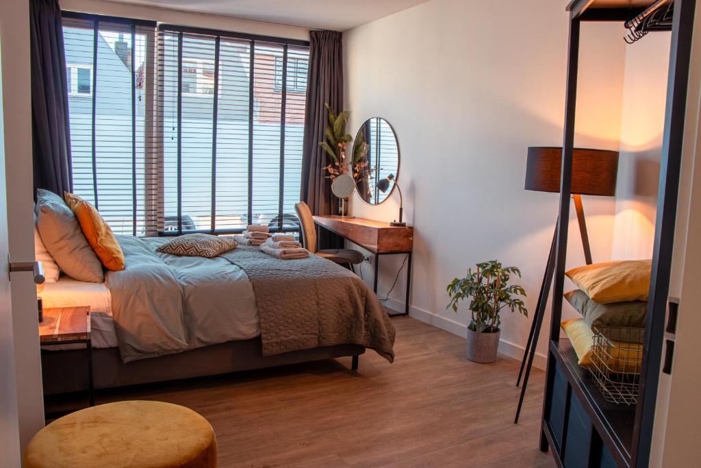 a bedroom with a bed and a desk and a window at Boutique Suites Deluxe in Middelburg