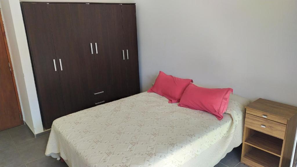 1 dormitorio con 1 cama con 2 almohadas rosas en Lofts en la Sierra!! en Villa Carlos Paz