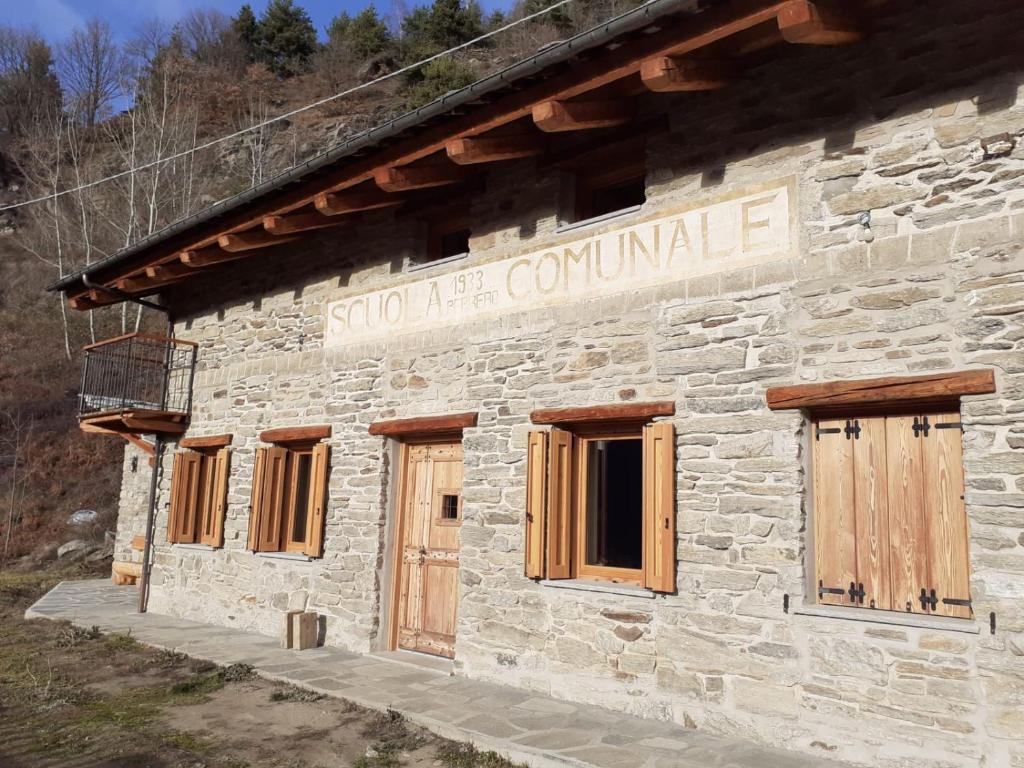 a stone building with wooden doors and a sign on it at La scuola in Riclaretto