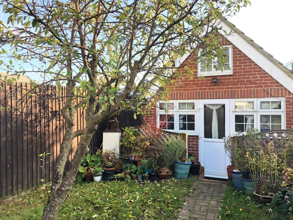 una casa con un árbol en el patio delantero en The Artist’s Hideaway. en Woking