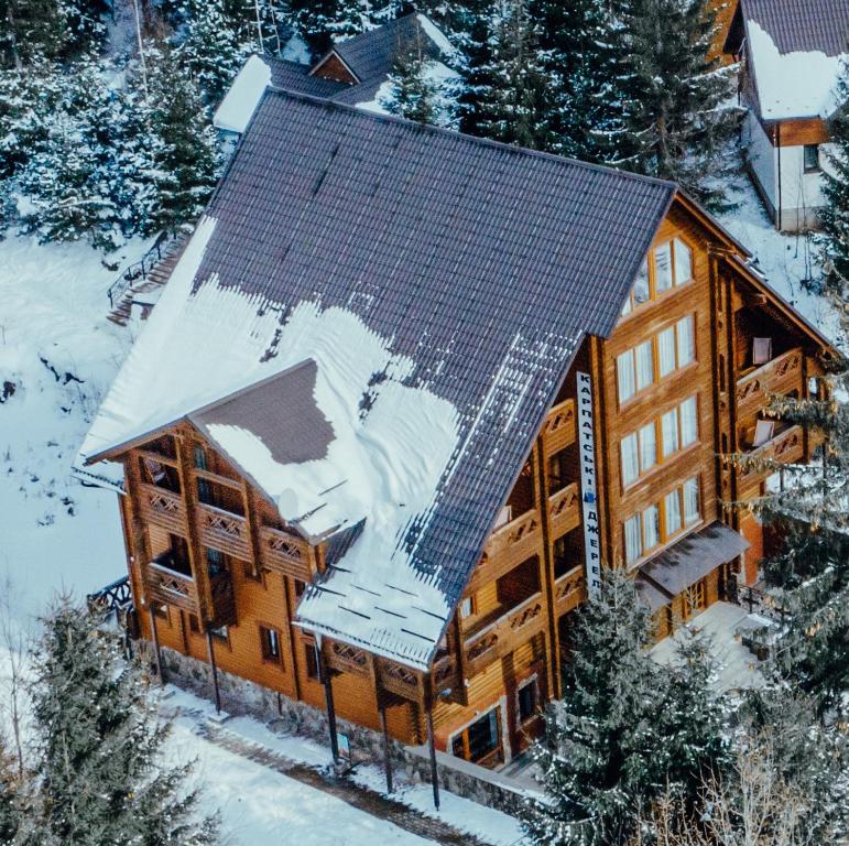 una vista aerea di una baita di tronchi con neve sul tetto di Karpatski Dzherela a Jaremče