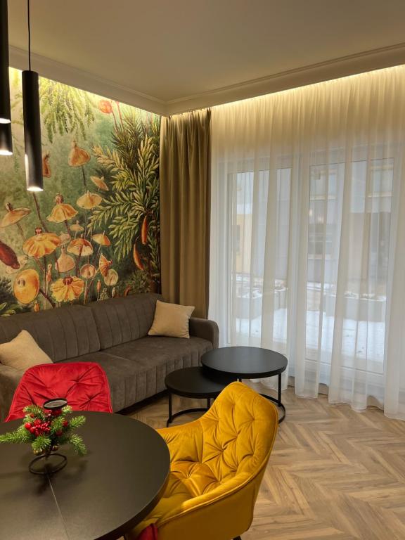 Apartament Sweet Dream Longinówka في برودنيتسا: غرفة معيشة بها أريكة وطاولات ولوحة