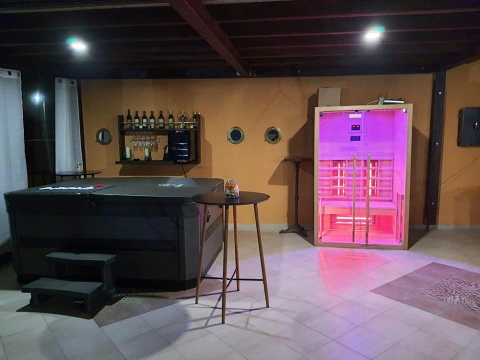 a bar with pink lighting in a room with a table at Kuća za odmor Primavera in Vinkovci