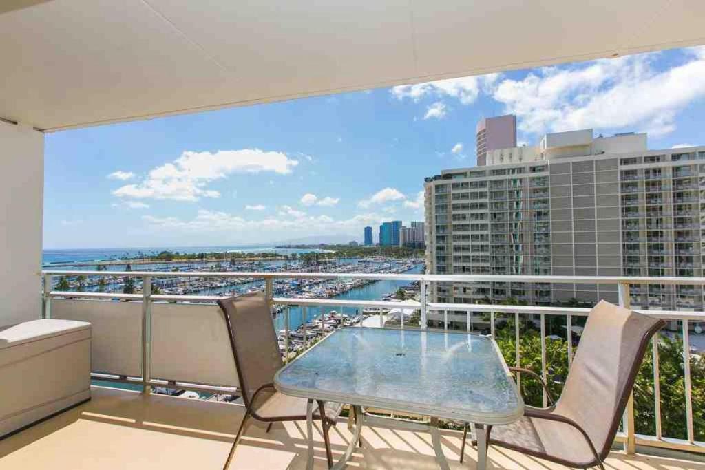 balcone con tavolo, sedie e vista sulla città di Ilikai Tower 1033 Yacht Harbor View 1BR a Honolulu