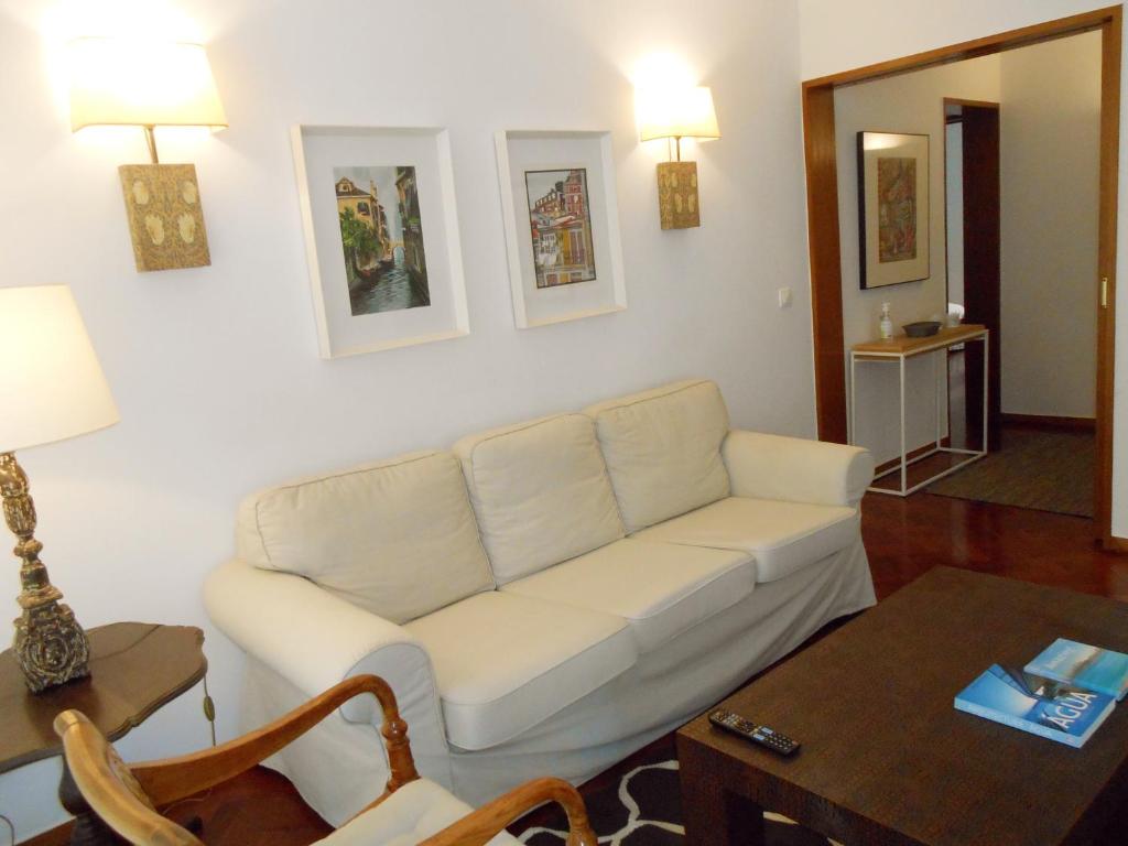 ein Wohnzimmer mit einem weißen Sofa und einem Tisch in der Unterkunft Cacao Estoril Apartment in Estoril