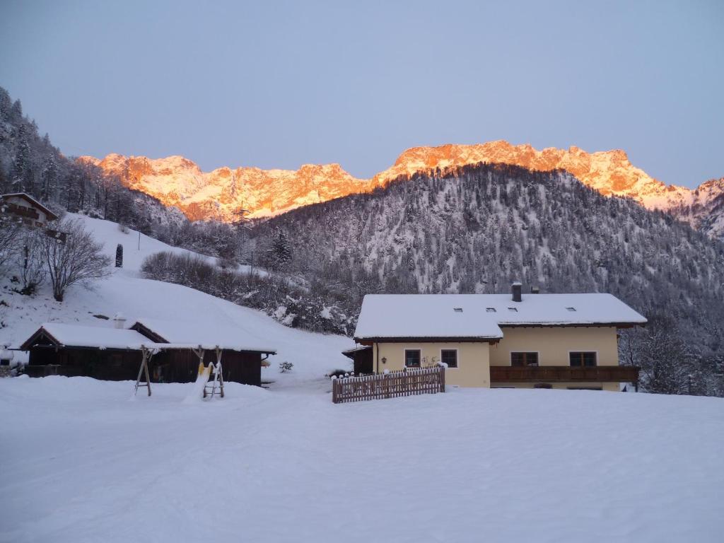 a house in the snow in front of a mountain at Ferienwohnung Feichtlgütl in Marktschellenberg