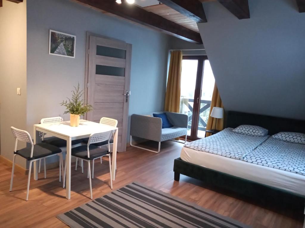 1 dormitorio con 1 cama, mesa y sillas en Mazurska Apartamenty, en Rydzewo