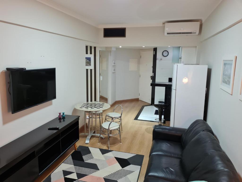 a living room with a couch and a tv and a table at Flat Centro Campinas - L'Hirondelle 125 in Campinas