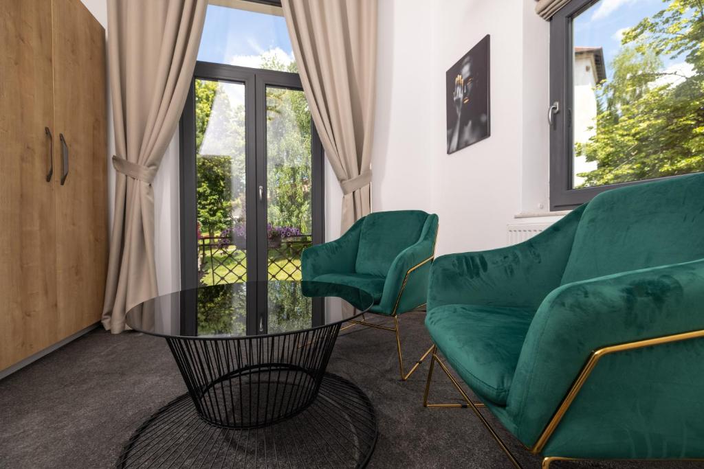 uma sala de estar com duas cadeiras verdes e uma mesa de vidro em Haller Boutique em Târgu-Mureş