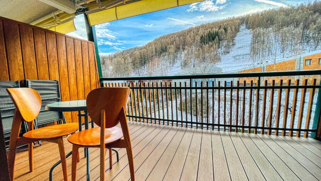 einen Balkon mit einem Tisch und Stühlen sowie einem großen Fenster in der Unterkunft Appartamento Smith Grignolino - Affitti Brevi Italia in Bardonecchia