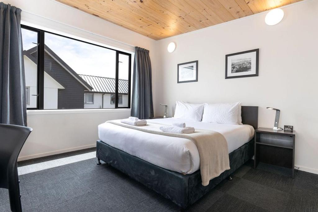 um quarto com uma cama grande e uma janela grande em The Bealey Quarter em Christchurch