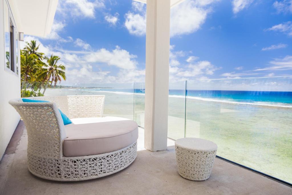 a white chair on a balcony with a view of the ocean at Ocean Spray Villas in Rarotonga