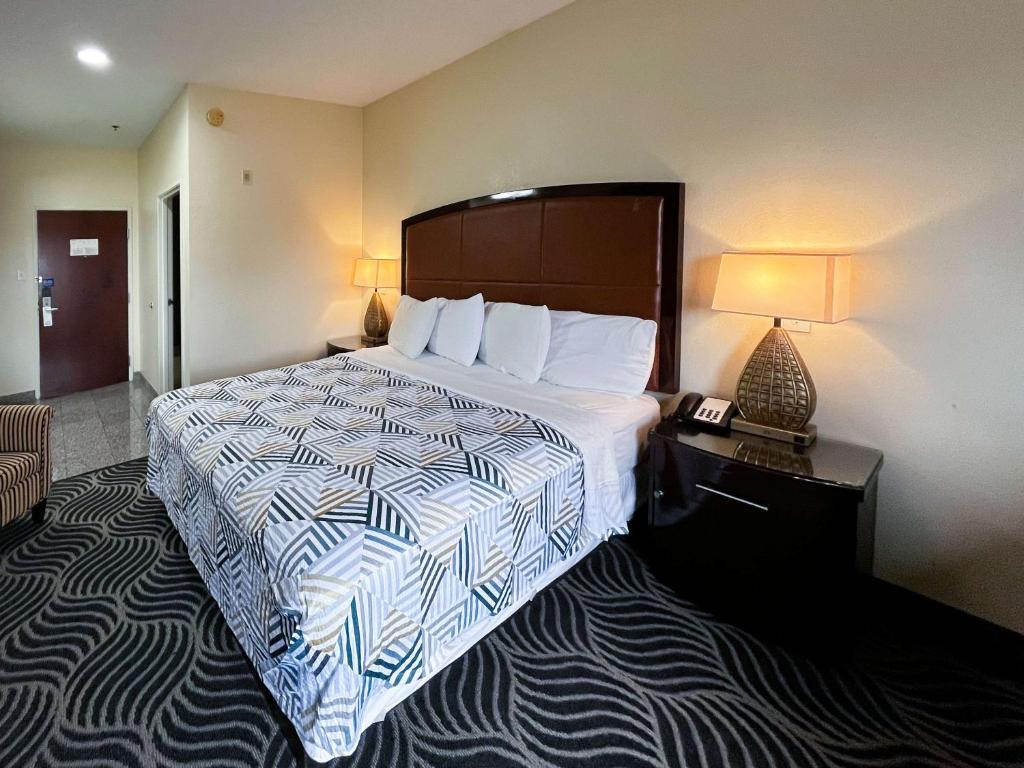 una habitación de hotel con una cama grande y una lámpara en Executive Inn & Suites Breaux Bridge, LA, en Breaux Bridge