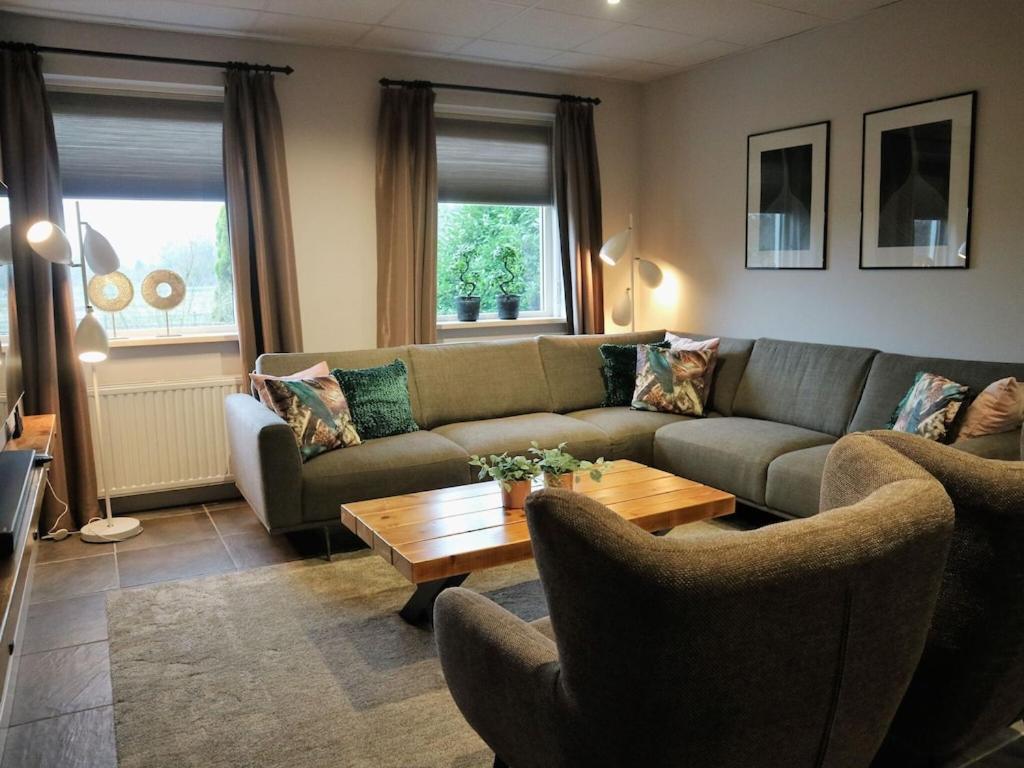 uma sala de estar com um sofá e uma mesa de centro em Holiday home with a view of the riding school em Eibergen