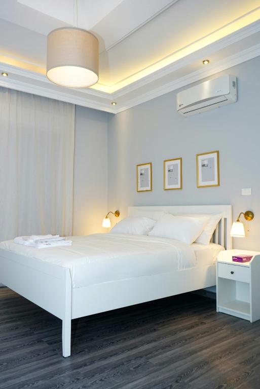 a white bedroom with a large white bed and a table at Elite Corner Apartment in Ţāb Kirā‘