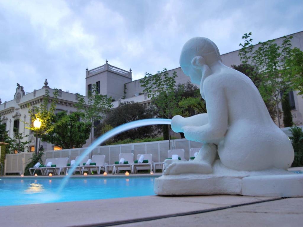 uma estátua de um homem sentado ao lado de uma fonte em Hotel Balneario Prats em Caldes de Malavella